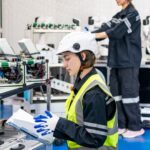 Female Engineer check and control automation robot arms machine in intelligent factory industrial on real time monitoring system software. robotics and digital manufacturing operation.