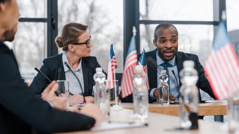 selective focus of attractive businesswoman looking at african american diplomat
